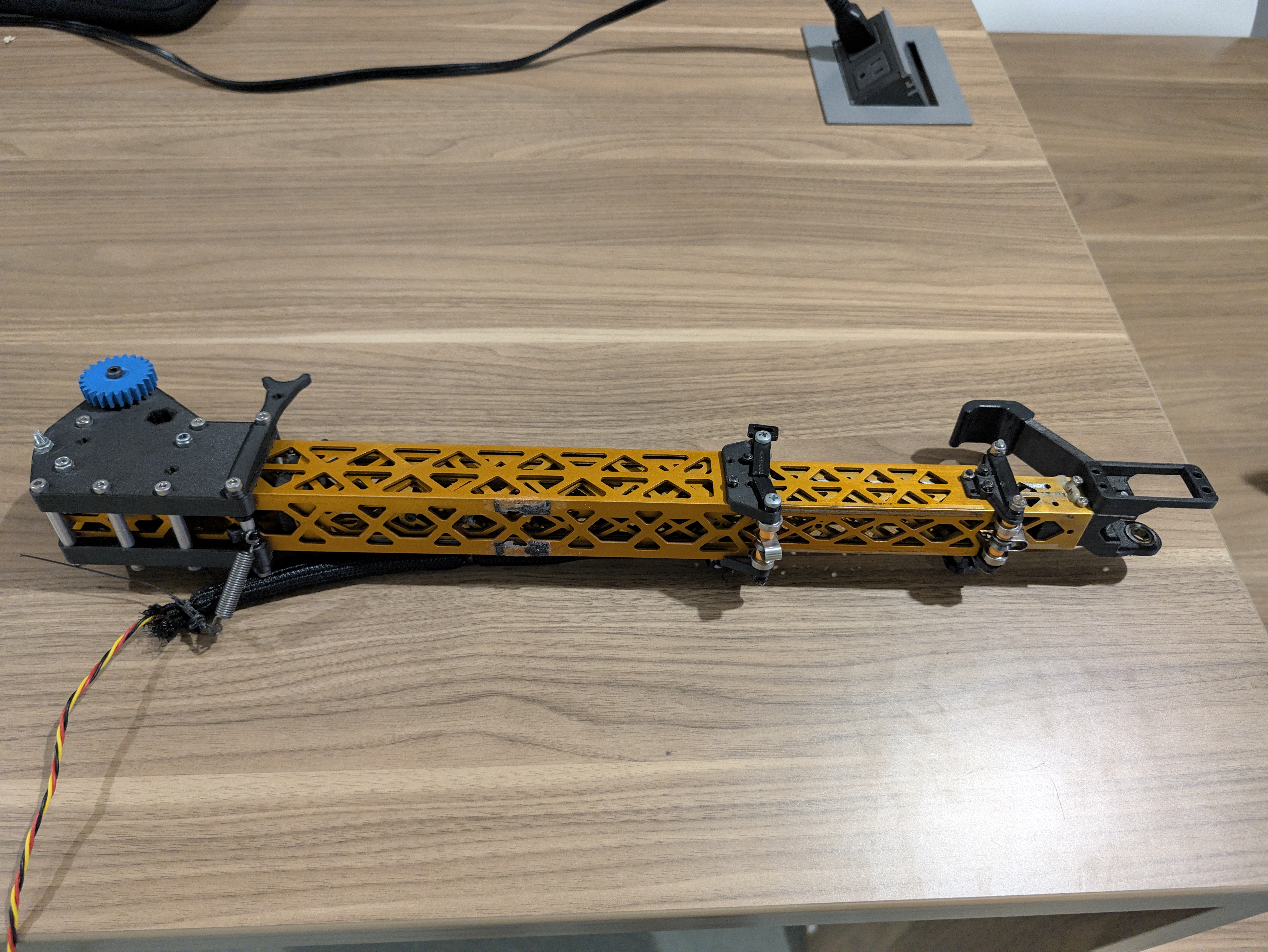 Robot arm assembly with a long gold metal tube and black printed end components