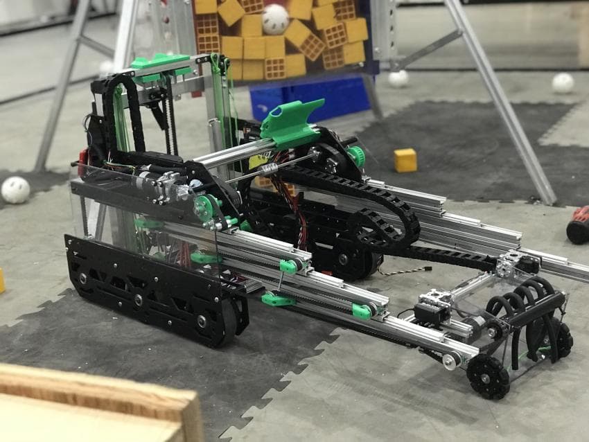 FTC robot with green custom cradle, upright brackets, pulley-like components, and slide fittings highlighted