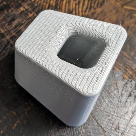 White printed part with visible extrusion lines on its top surface